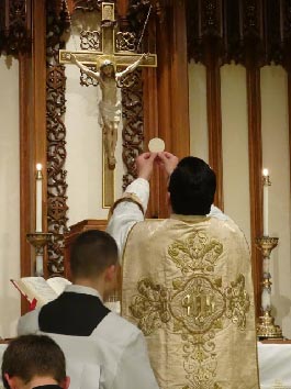 el sacerdote, elevando la Sagrada Hostia entre el cielo y la tierra